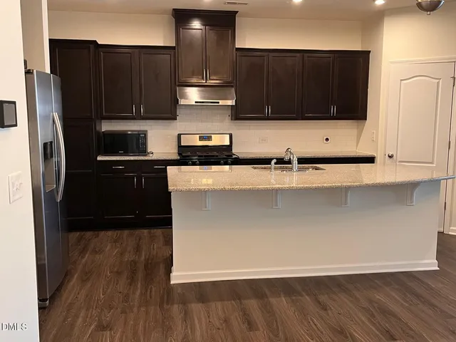 a kitchen with stainless steel appliances wooden cabinets and a wooden floor