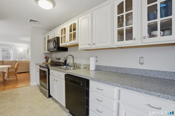 a kitchen with stainless steel appliances granite countertop a sink and cabinets with granite countertops next to a window