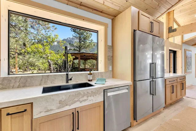 a kitchen with stainless steel appliances granite countertop a refrigerator a stove and a sink with wooden floor