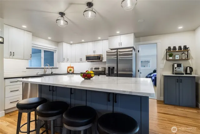 a kitchen with stainless steel appliances granite countertop a sink a stove a refrigerator cabinets and chairs