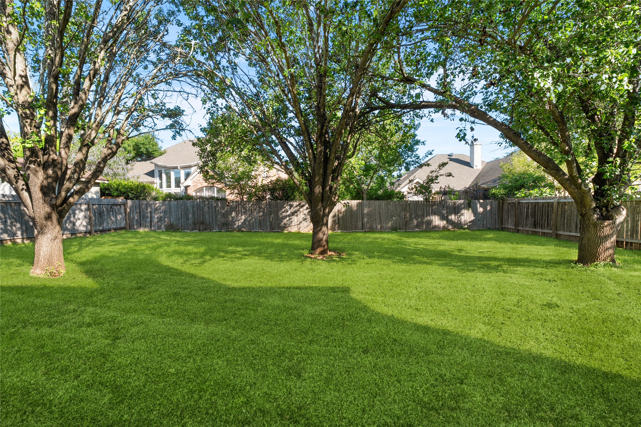 206 River Down Road Georgetown, TX 78628 - Photo 33 of 39 Expansive backyard featuring a lush lawn, mature trees, and a wooden privacy fence
