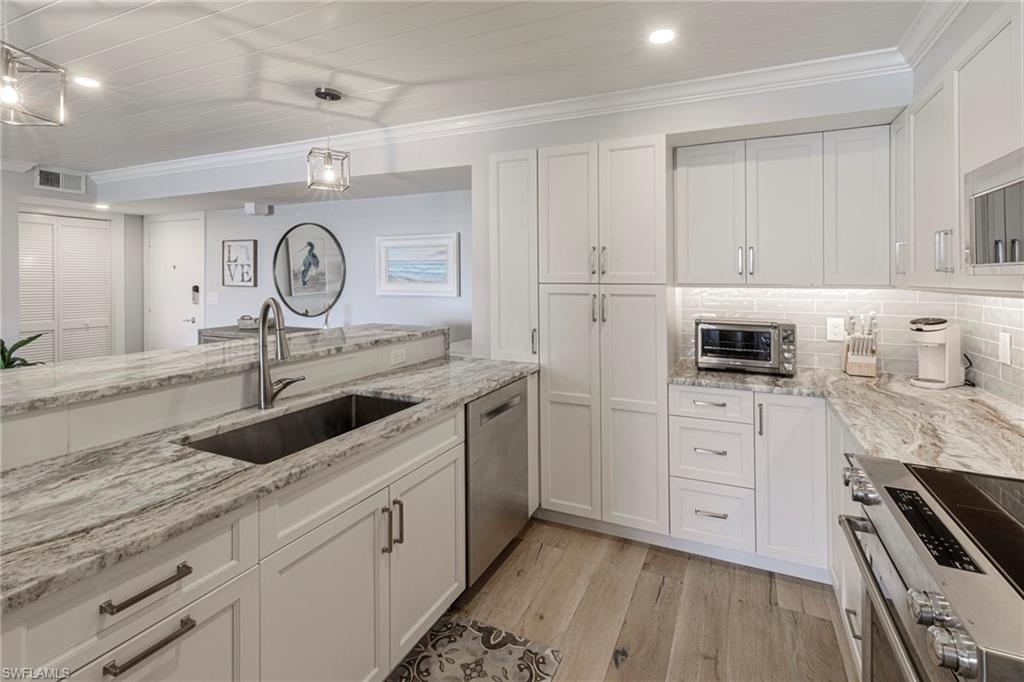 250 Park Shore Drive, Unit 302 Naples, FL 34103 - Photo 12 of 35 a kitchen with granite countertop a sink a stove and cabinets