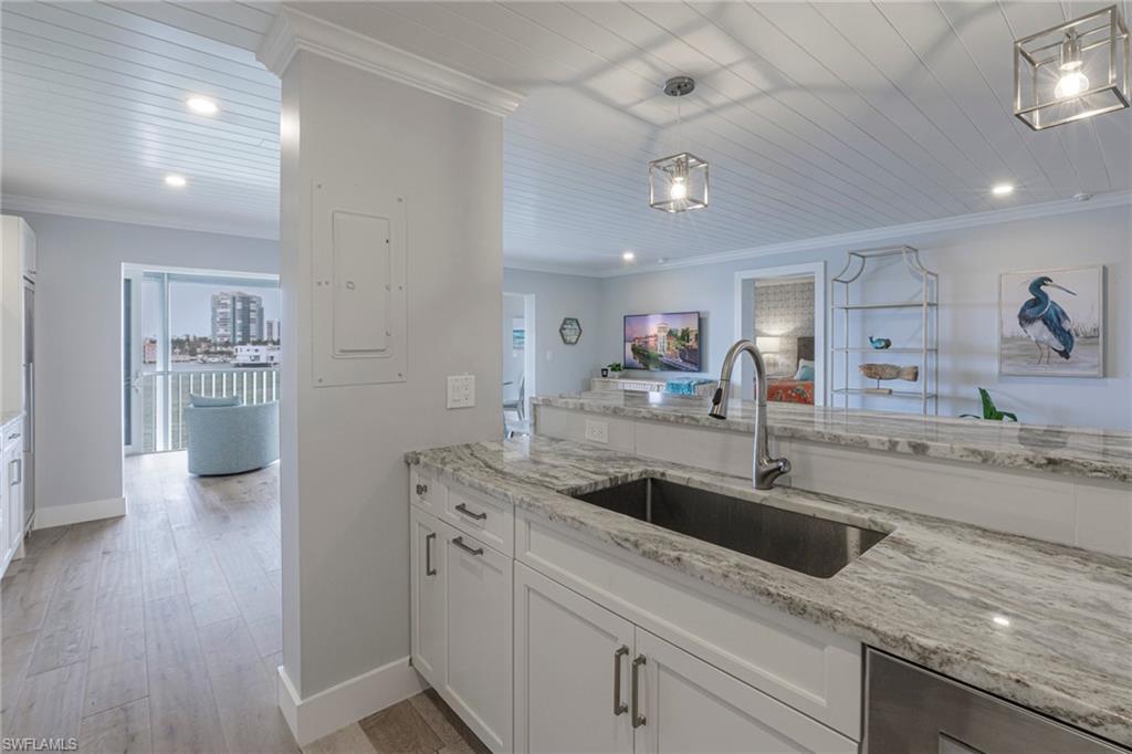 250 Park Shore Drive, Unit 302 Naples, FL 34103 - Photo 13 of 35 a kitchen with granite countertop a sink and a refrigerator