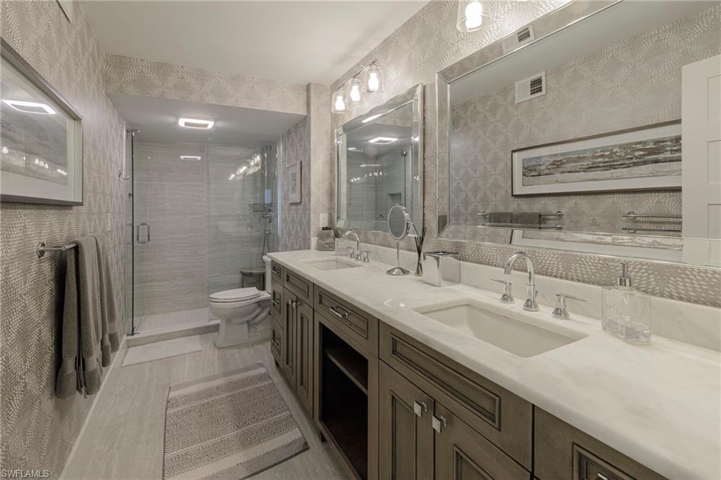 250 Park Shore Drive, Unit 302 Naples, FL 34103 - Photo 18 of 35 a bathroom with a double vanity sink a toilet and a mirror