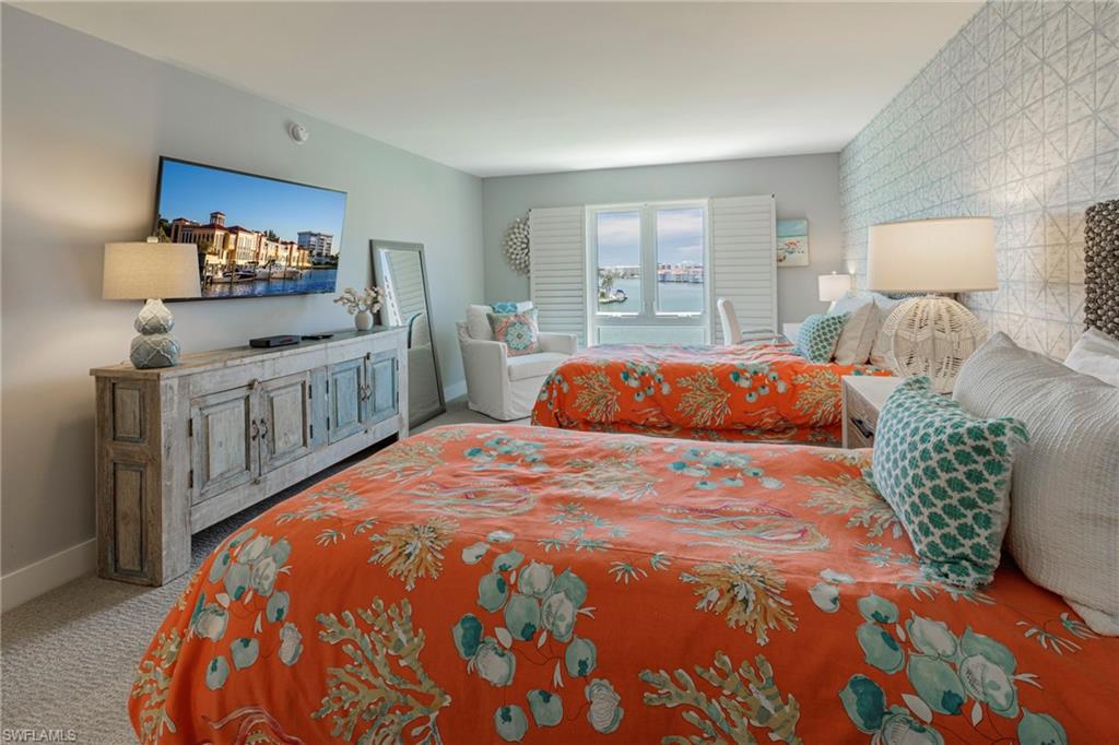 250 Park Shore Drive, Unit 302 Naples, FL 34103 - Photo 26 of 35 a bedroom with a large bed and a flat tv screen