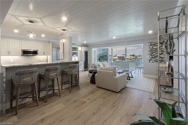 a living room with stainless steel appliances furniture and a kitchen view