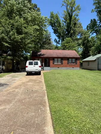 a view of house with yard and car parked
