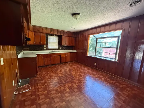 a room with kitchen island granite countertop a sink appliances and cabinets
