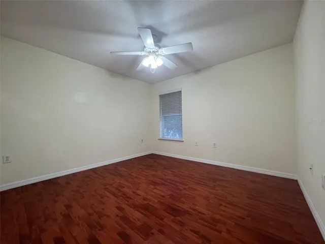 an empty room with wooden floor and fan