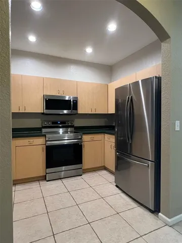 a kitchen with granite countertop a refrigerator and a stove top oven