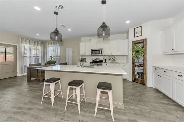 a kitchen with stainless steel appliances kitchen island granite countertop a stove a sink a dining table and chairs with wooden floor