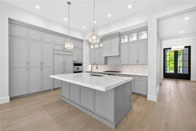 a kitchen with white cabinets a sink dishwasher and a stove with wooden floor