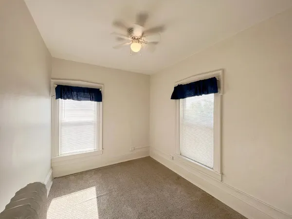 an empty room with windows and fan