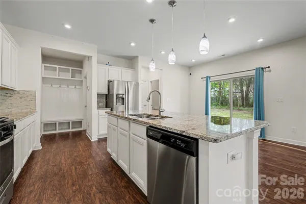 a kitchen with granite countertop kitchen island wooden floors and stainless steel appliances