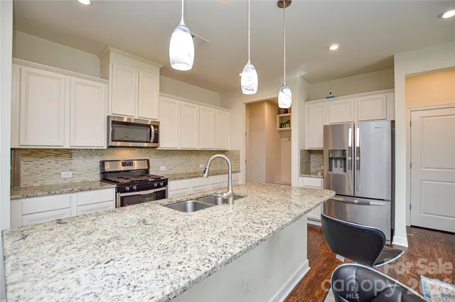 a kitchen with stainless steel appliances granite countertop a sink refrigerator and microwave