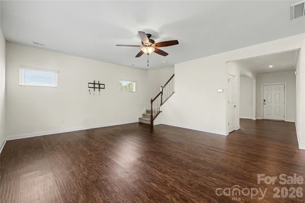 an empty room with wooden floor ceiling fan and windows