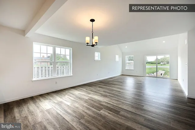 an empty room with wooden floor chandelier and windows