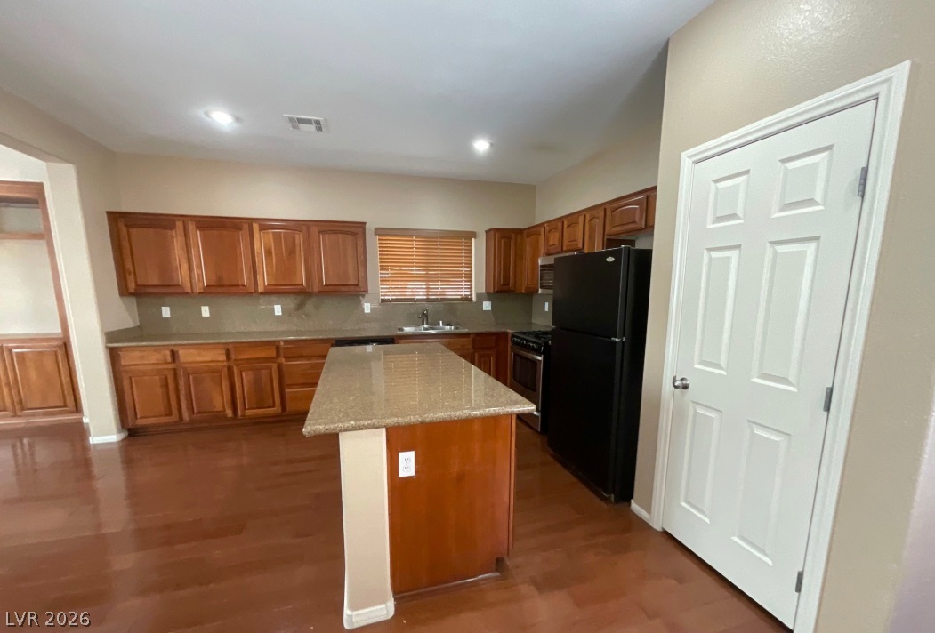 10841 Paradise Road Henderson, NV 89052 - Photo 9 of 35 A well-lit kitchen with rich wood cabinetry and a functional island centerpiece.