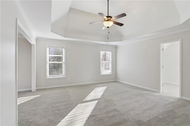 an empty room with a chandelier fan and windows