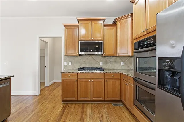 a kitchen with stainless steel appliances granite countertop a stove a sink and a refrigerator