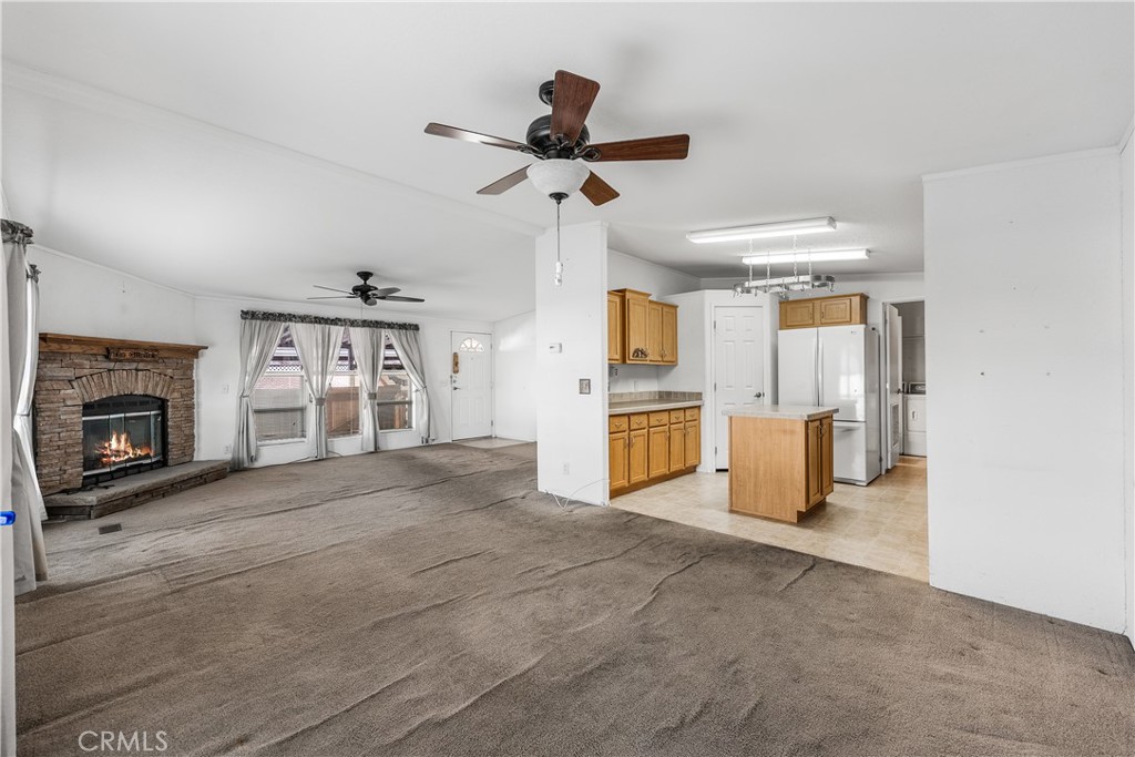 600 South Dennison, Unit 109 Tehachapi, CA 93561 - Photo 10 of 43 a view of a livingroom with a fireplace a ceiling fan a kitchen microwave and a refrigerator