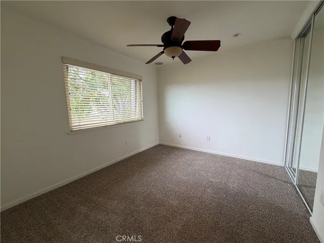 an empty room with windows and ceiling fan