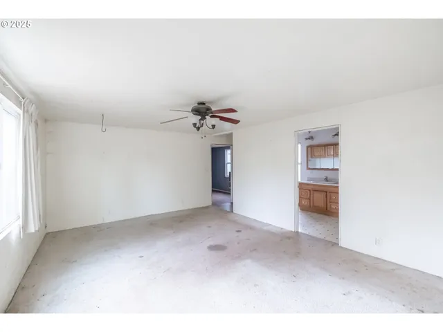 an empty room with a ceiling fan and window