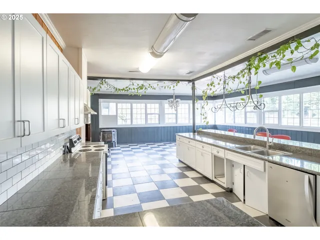 a large white kitchen with a large window and refrigerator