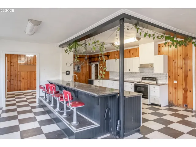 a kitchen with a stove a sink dishwasher and a dining table with wooden floor