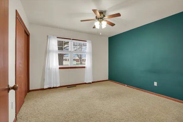 a view of an empty room and chandelier fan