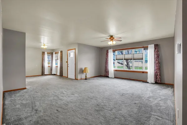an empty room with windows and ceiling fan