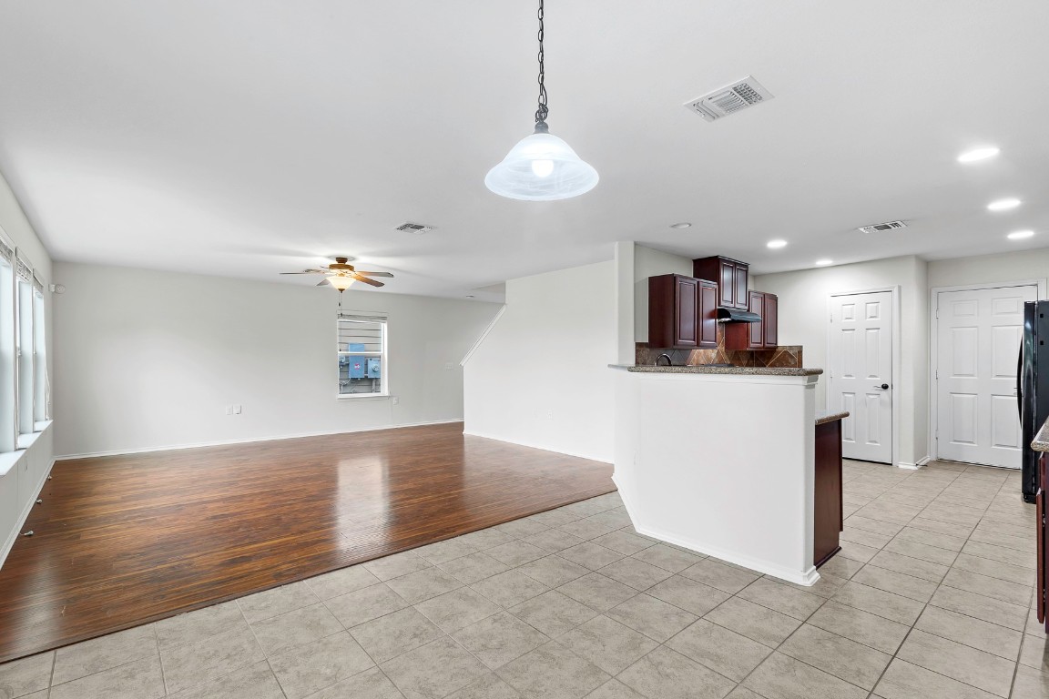 11412 Barns Trail Austin, TX 78754 - Photo 20 of 20 Kitchen with light tile patterned floors, decorative light fixtures, dark brown cabinets, open floor plan, and plenty of natural light