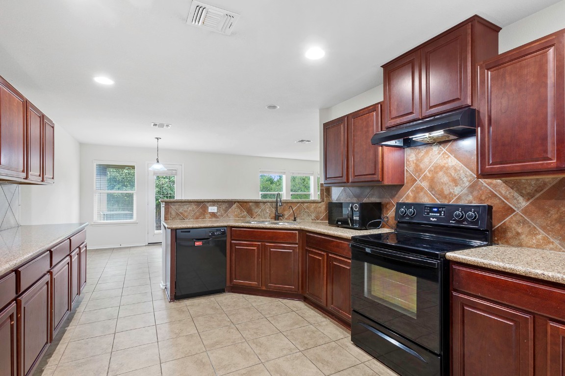 11412 Barns Trail Austin, TX 78754 - Photo 6 of 20 Kitchen featuring tasteful backsplash, black appliances, dark brown cabinets, light tile patterned floors, and decorative light fixtures