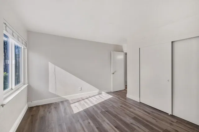a view of hallway with window and wooden floor