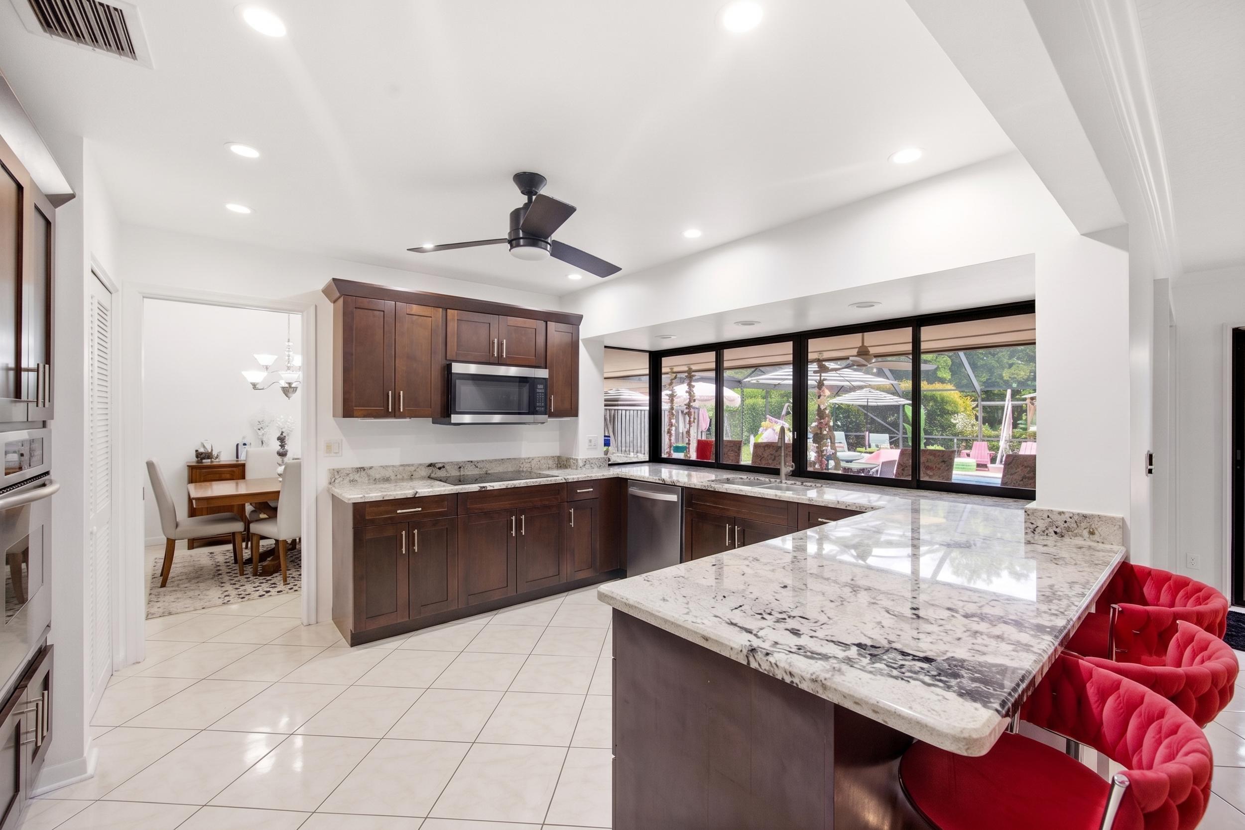 375 Northwest 53rd Street Boca Raton, FL 33487 - Photo 7 of 14 a kitchen with stainless steel appliances granite countertop a sink counter space and a stove top oven