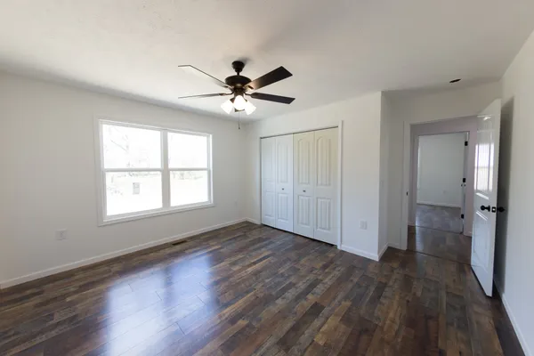 a view of an empty room with wooden floor and a window