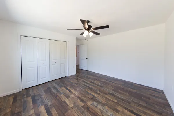 a view of a room with wooden floor and a ceiling fan