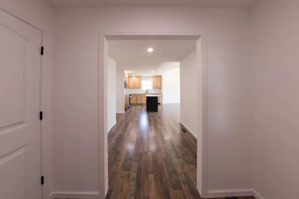 a view of a hallway with wooden floor and a bathroom