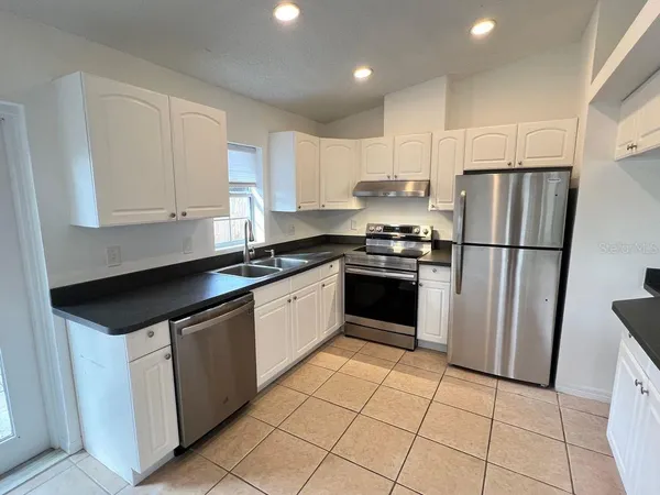 a kitchen with granite countertop a refrigerator sink and cabinets