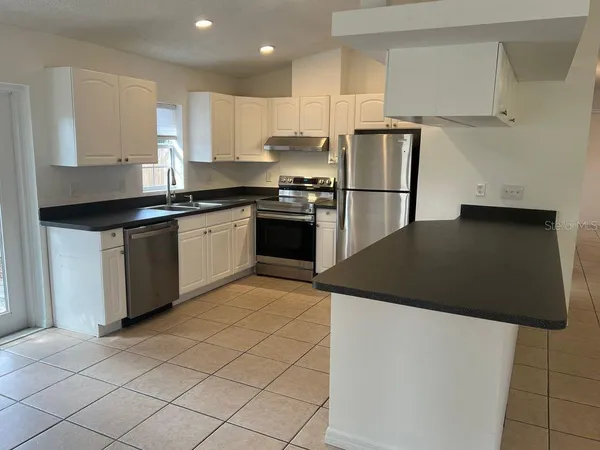 a kitchen with stainless steel appliances granite countertop a refrigerator a stove and a sink