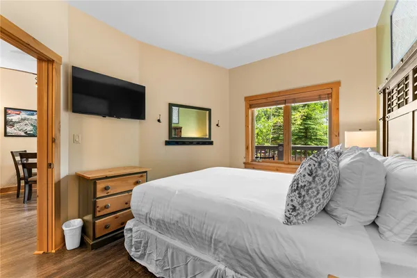a bedroom with a large bed and a flat tv screen on dresser
