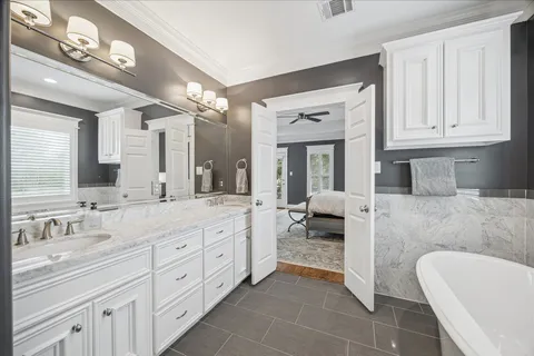 a spacious en suite bathroom with a granite countertop tub and a double vanity sink