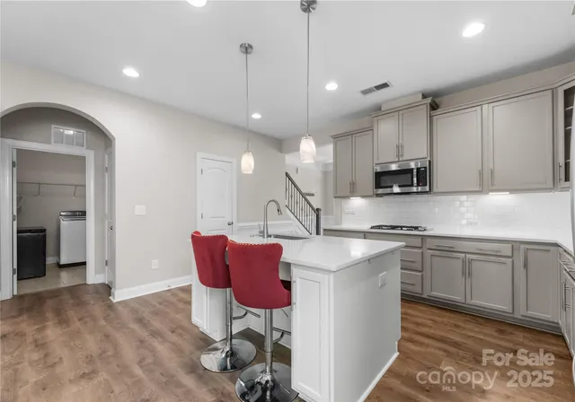 a kitchen with stainless steel appliances granite countertop a sink a stove a refrigerator and island with wooden floor