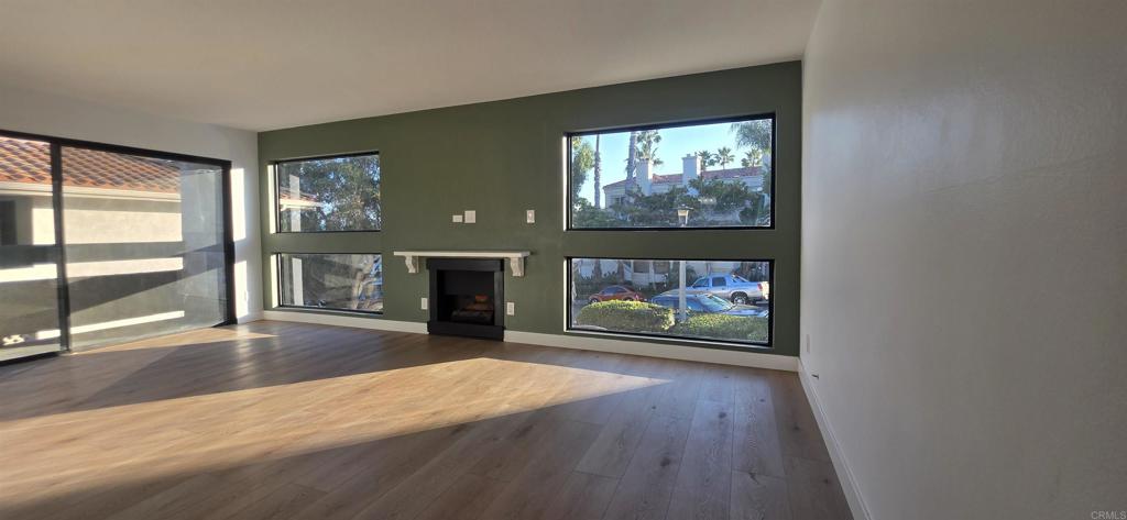 2306 Altisma Way, Unit 116 Carlsbad, CA 92009 - Photo 12 of 17 an empty room with wooden floor fireplace and windows