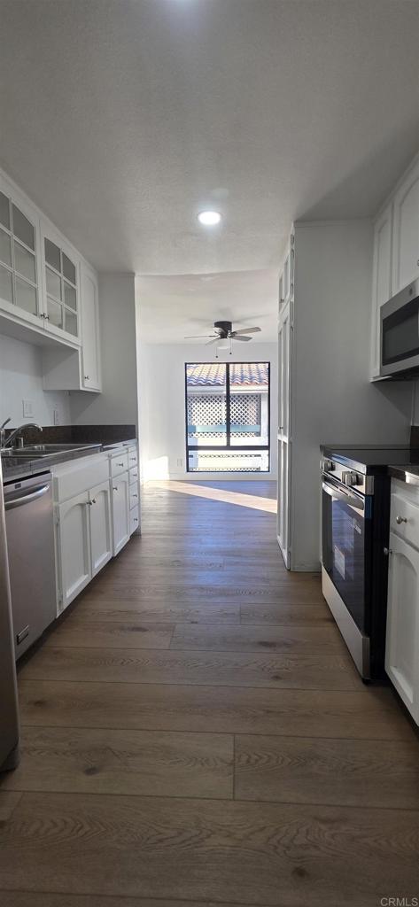 2306 Altisma Way, Unit 116 Carlsbad, CA 92009 - Photo 2 of 17 a kitchen with stainless steel appliances granite countertop a stove a sink and a wooden floors