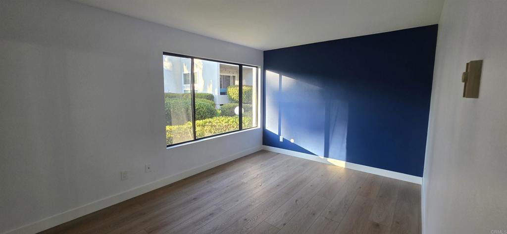 2306 Altisma Way, Unit 116 Carlsbad, CA 92009 - Photo 5 of 17 an empty room with wooden floor and windows