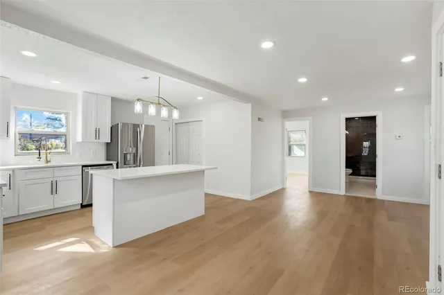 a large kitchen with white cabinets a sink dishwasher and a stove with wooden floor
