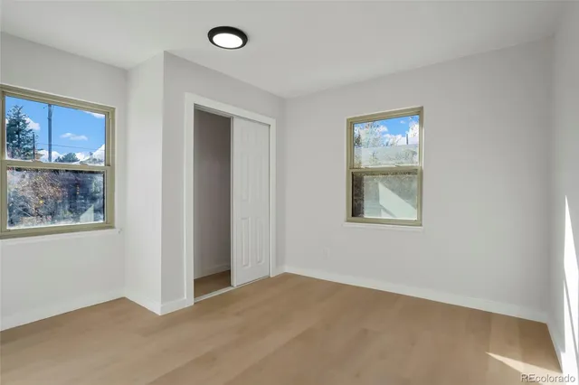 a view of an empty room with window and wooden floor