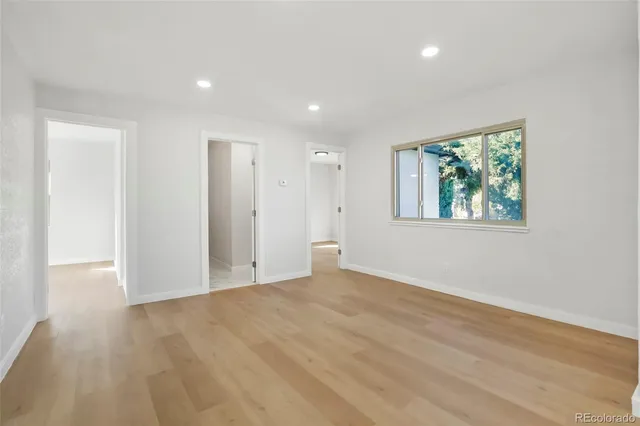 a view of an empty room with wooden floor and a window