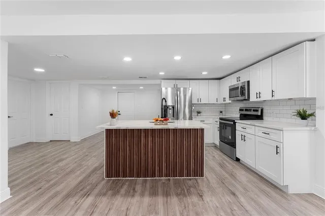 a kitchen with stainless steel appliances granite countertop a sink stove and white cabinets with wooden floor